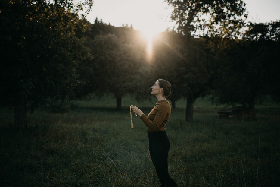 Frau steht ruhig in meditativer Haltung – Symbol für innere Sicherheit und Stabilität jenseits äußerer Kontrolle.